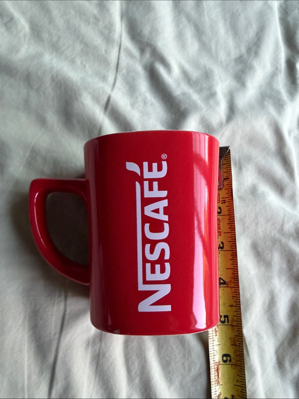 red NESCAFÉ branded ceramic mug with white lettering.